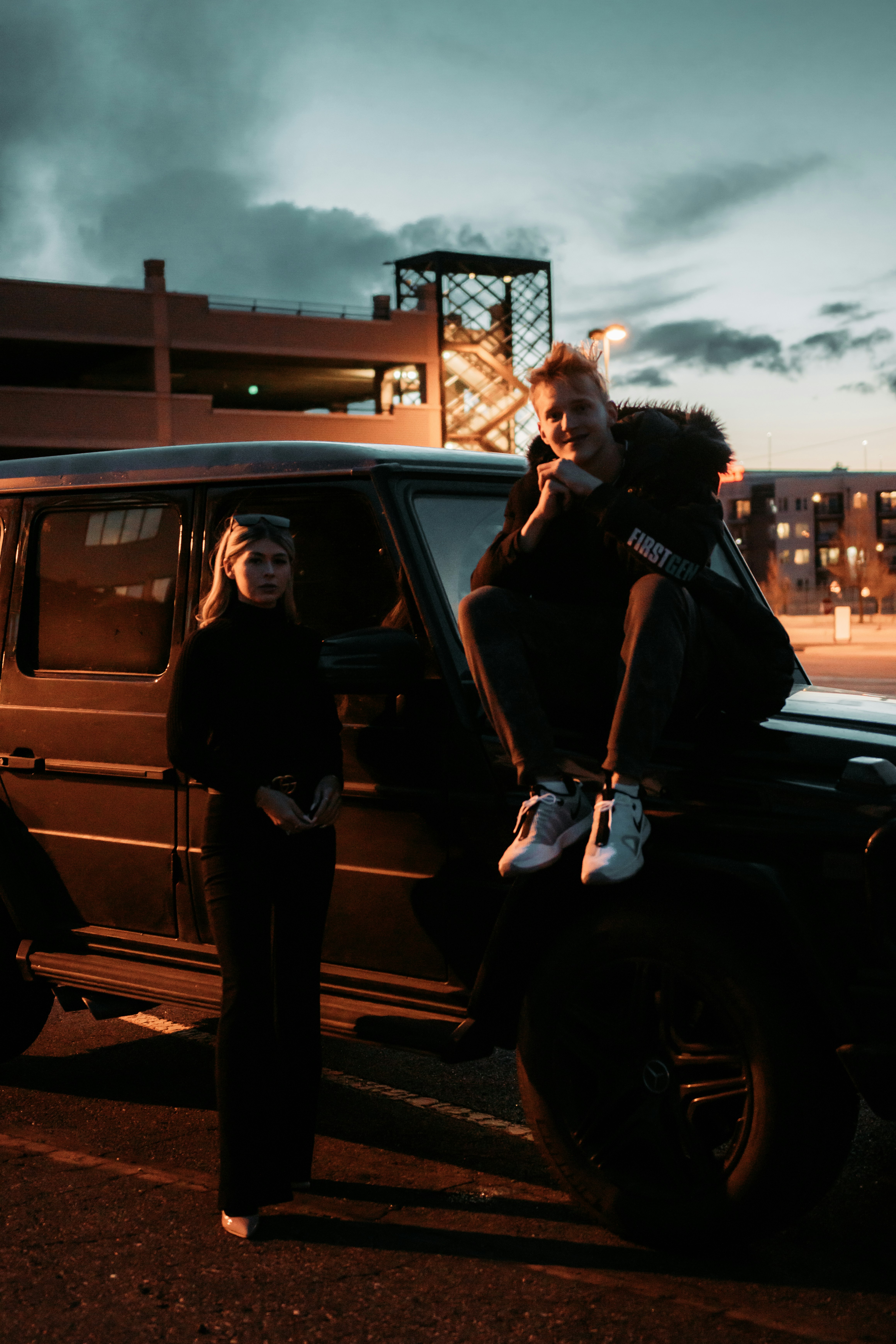 man in black jacket standing beside black suv during night time